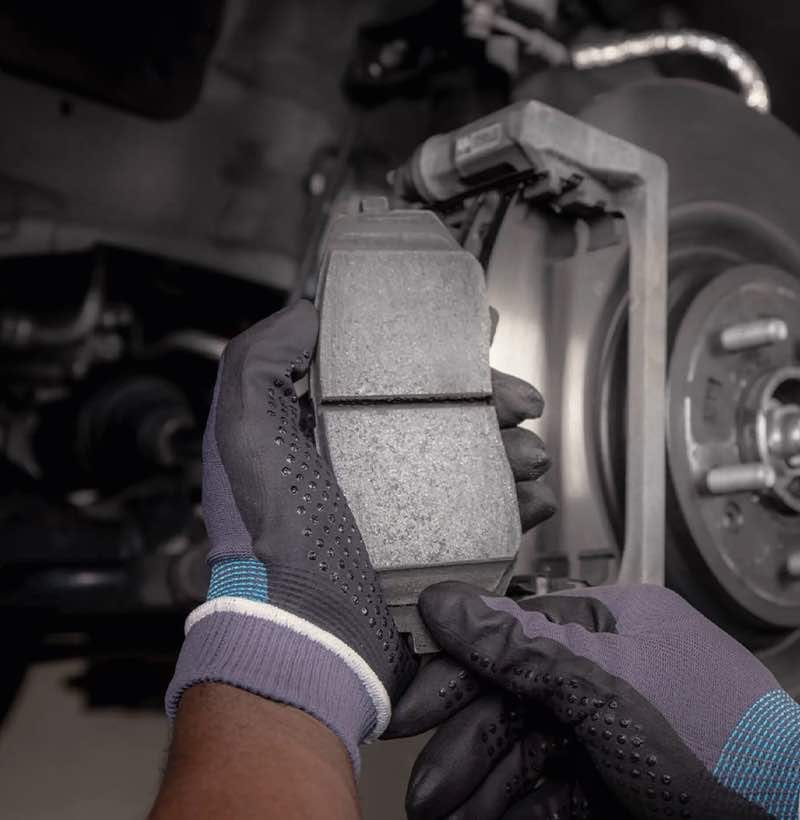 Ein Kia Techniker ersetzt die abgenutzten Bremsbeläge und Bremsscheiben eines älteren Kia durch Kia Originalteile.